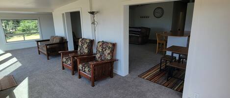Un espacio habitable de concepto abierto con un gran ventanal, piso alfombrado y muebles de madera.