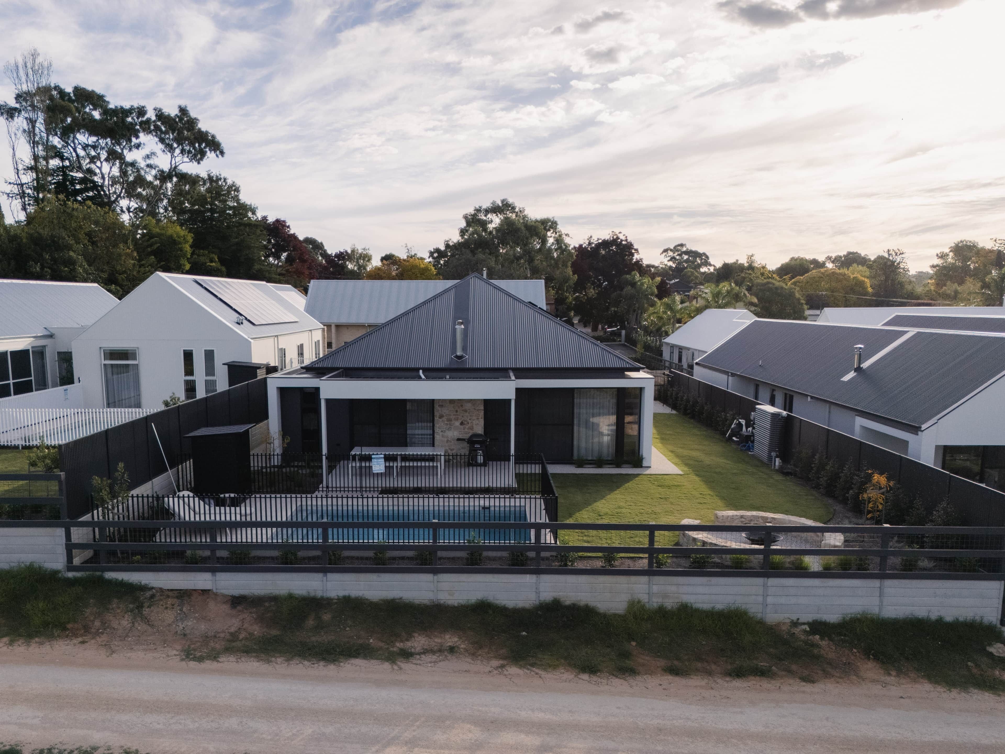 A modern residential area with detached houses, a swimming pool, and a well-maintained lawn.