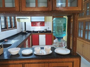 Cocina con gabinetes de madera, dispensador de agua y lavamanos.