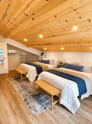 A bedroom with two beds, wooden ceiling, and a built-in bench.