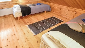 A small, wooden-paneled room with a loft bed, a lower bunk bed, and a window with blinds.