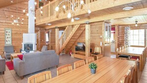 Ein großzügiger Holzraum mit Essbereich, Sofa, Fernseher und Treppe.