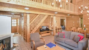 Ein Holzinnenraum mit Kamin, Sofa und Essbereich.