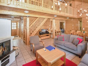 Ein Holzinnenraum mit Kamin, Sofa und Essbereich.