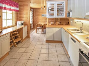 A kitchen with wooden cabinets, a sink, and a dishwasher. - Joutsen by Interhome (Loviisa)