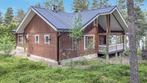 Eine Holzhütte mit Veranda, umgeben von Bäumen und Grünpflanzen.