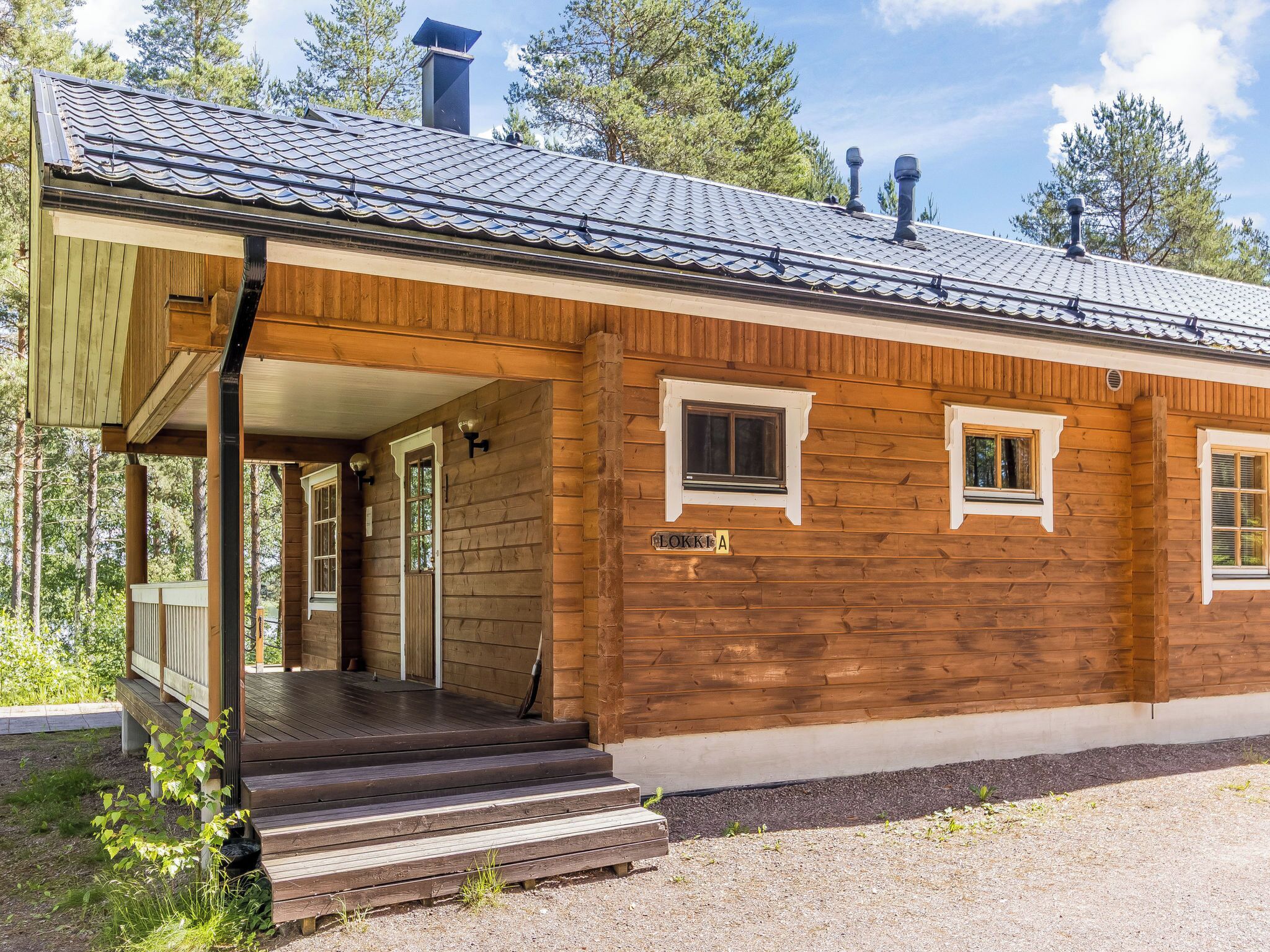 En træhytte med veranda, skorsten og et skilt med teksten 'LOKKI A'.