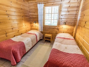 Une cabine avec deux lits, une fenêtre avec des rideaux et une petite table.