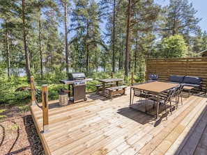 A deck with a grill, picnic table, and outdoor seating.