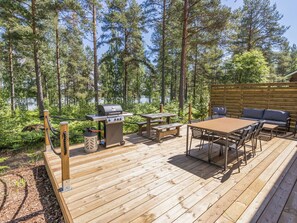Eine Terrasse mit Grill, Picknicktisch und Gartenmöbeln.