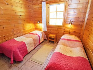 A cabin-style room with two beds, a small table, and a window.