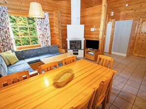 A wooden cabin interior with a sofa, dining table, chairs, a television, and a fireplace. - Vacation home Tiira by Interhome (Loviisa)