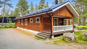 Een houten hut met een veranda, schoorsteen en een grindpad.