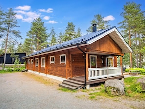 Une cabane en bois avec un porche, une cheminée et une allée gravillonnée.