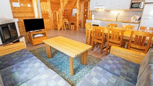 Een houten interieur met een televisie, houten meubels, een keuken en een trap.