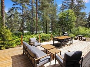 Une terrasse dotée de mobilier d’extérieur, d’un barbecue et offrant une vue sur une forêt.