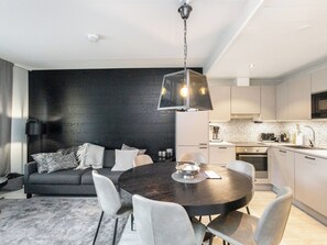 A modern kitchen with white cabinets, a black countertop, and a hanging light fixture. - Levin kunkku b2 by Interhome (Kittilä)