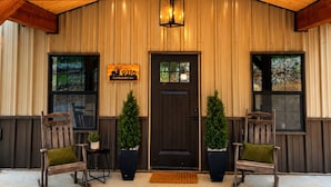 Un edificio con facciata in legno, una porta d'ingresso scura e due vasi con piante ai lati.