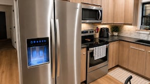 Una cucina moderna con elettrodomestici in acciaio inossidabile, mobili in legno e un piano di lavoro nero.