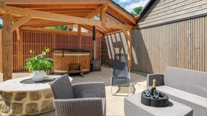 Eine Terrasse im Freien mit Korbmöbeln, einer Steinkaminanlage und einem überdachten Sitzbereich.