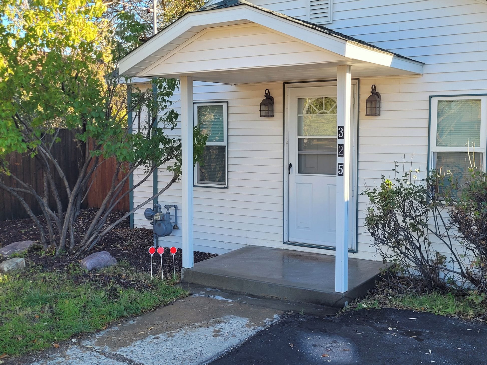 Une maison d’habitation avec un porche à l’avant, une porte de garage et une boîte aux lettres.