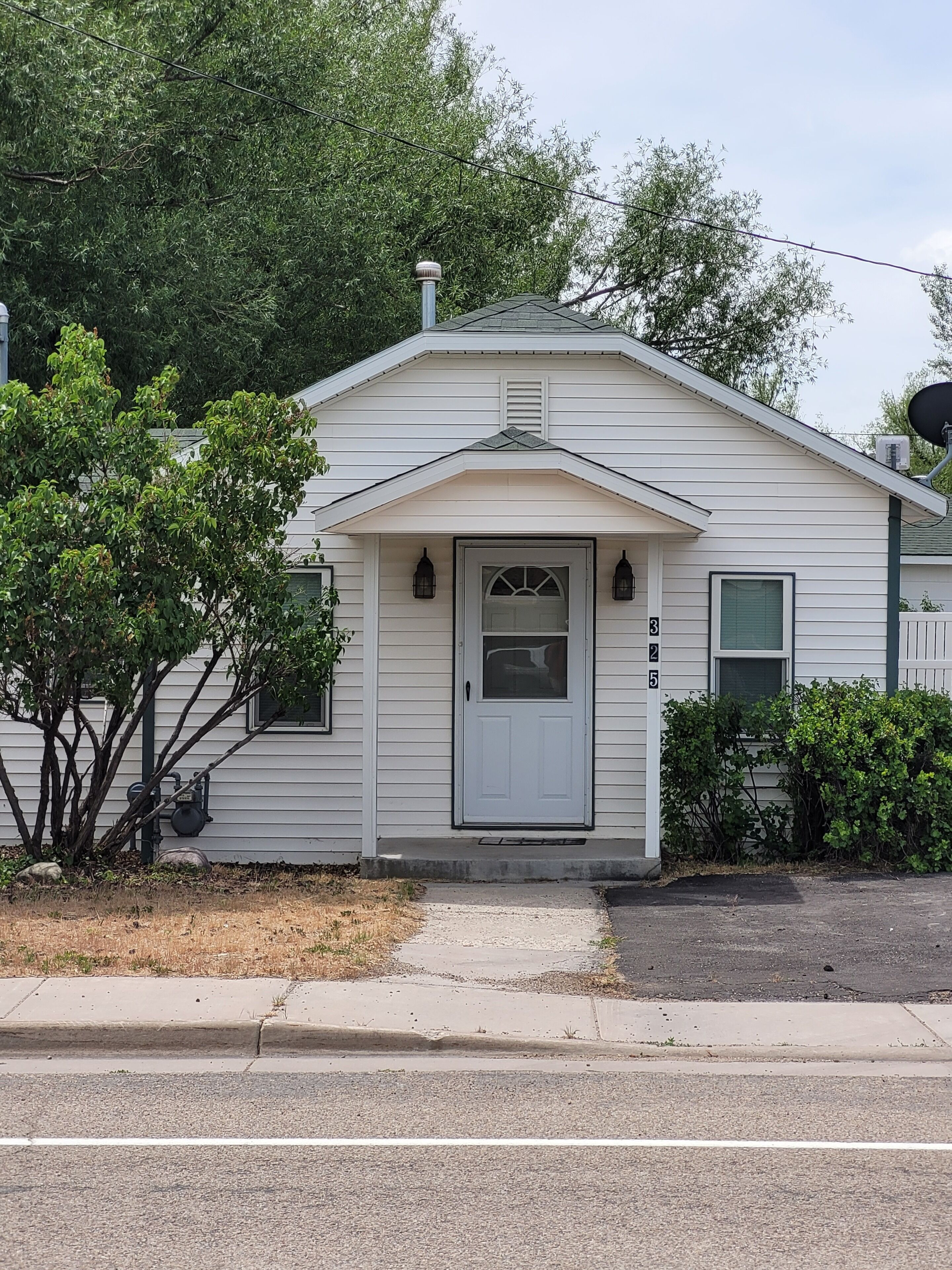 A single-story house with a white exterior, a front door, and a small porch area.