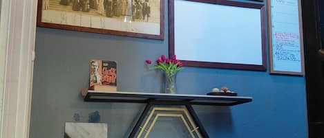 Une pièce avec une table hexagonale, une photographie encadrée, un livre et un vase rempli de fleurs.