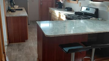 A kitchen with a central island, bar stools, a microwave, and a stove.