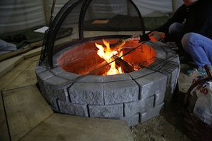 A stone fire pit with a metal grill and a mesh cover. - Chief Joseph, Large Tipi with central firepit (Markdale)