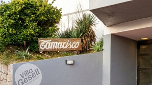 Una villa llamada 'Villa Gesell' con un cartel que dice 'Es Querer Volver' y una señal de madera encima.