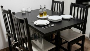 Una mesa de comedor con sillas, platos, cubiertos y aderezos.