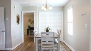 A dining area with a wooden table and chairs, a chandelier, and a view of a hallway. - Family Beach Retreat,  Arcade, Fire Pit, Dog Friendly (Surf City)