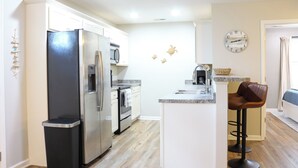 A modern kitchen with stainless steel appliances, a central island, and a bar stool. - Family Beach Retreat,  Arcade, Fire Pit, Dog Friendly (Surf City)