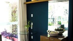 A room with a glass table, a wooden cabinet, a vase, and a potted plant. - Couple's Apartment with Sea View in Ponta Negra - EFM404 (Natal)