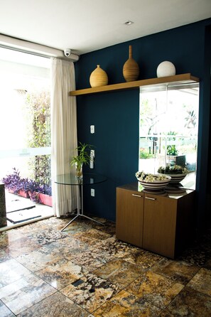 A room with a glass table, a wooden cabinet, a vase, and a potted plant. - Couple's Apartment with Sea View in Ponta Negra - EFM404 (Natal)