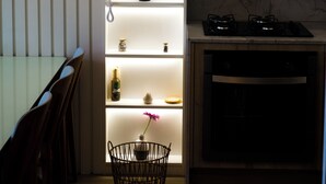 A modern kitchen with built-in shelves, a dining area with chairs, and a stove. - Couple's Apartment with Sea View in Ponta Negra - EFM404 (Natal)