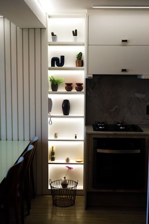 A modern kitchen with built-in shelves, a dining area with chairs, and a stove. - Couple's Apartment with Sea View in Ponta Negra - EFM404 (Natal)