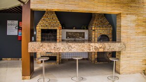 A brick-built outdoor kitchen with a countertop and stools. - Couple's Apartment with Sea View in Ponta Negra - EFM404 (Natal)
