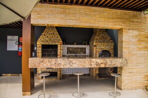 A brick-built outdoor kitchen with a countertop and stools. - Couple's Apartment with Sea View in Ponta Negra - EFM404 (Natal)