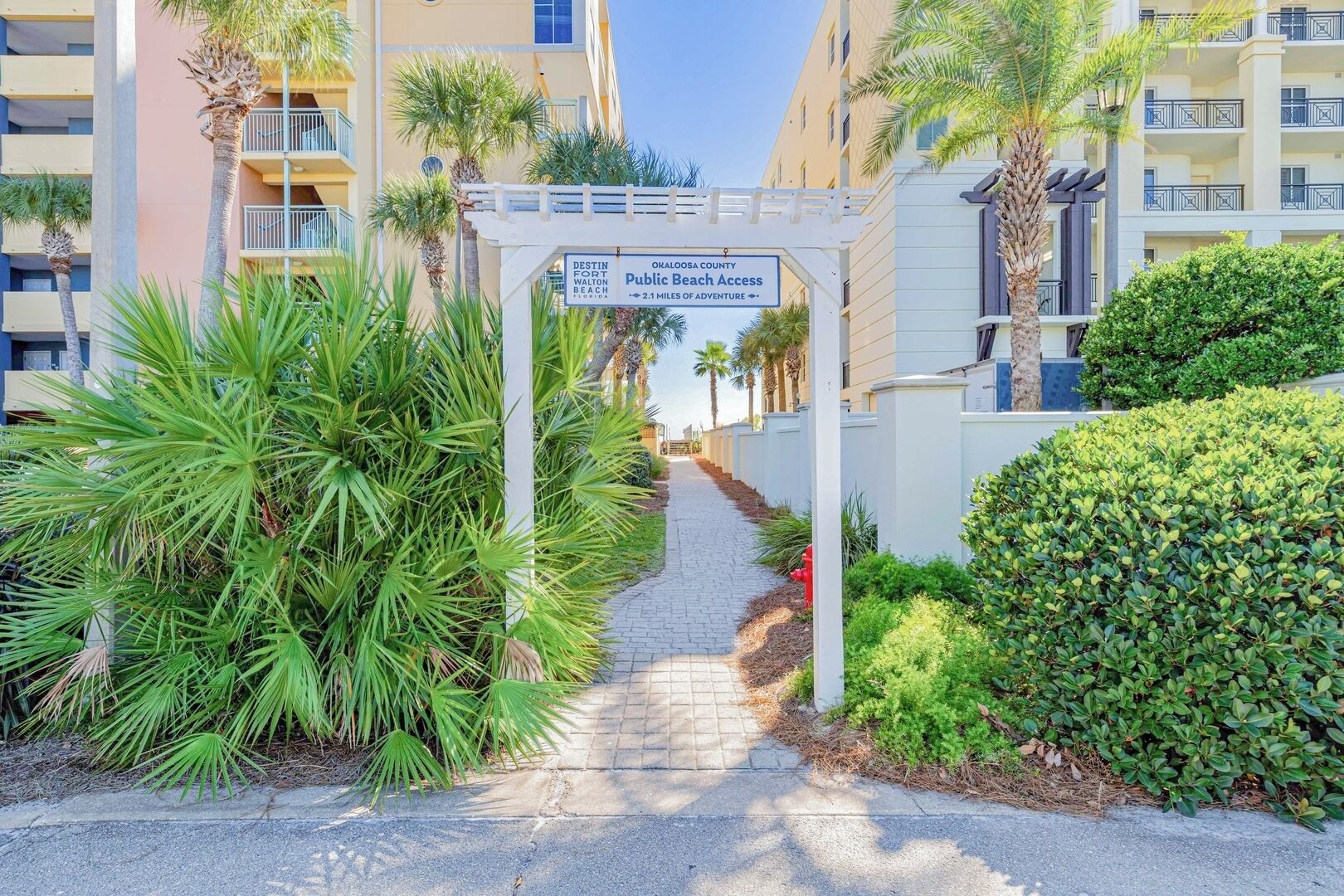 A pathway leading to a gated entrance with a sign indicating public beach access.