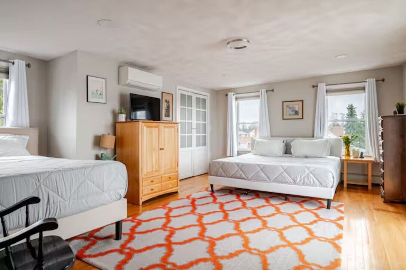 Une chambre avec deux lits, une armoire, un bureau et une fenêtre donnant sur un paysage agréable.