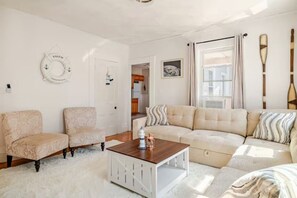 Una sala de estar con sofá, dos sillones, una mesita de centro y un adorno en la pared.