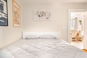 Un dormitorio con una cama, cabecera blanca y un cuadro enmarcado de un perro en la pared.