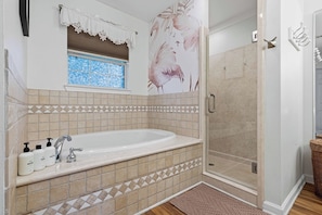 Un bagno con una vasca da bagno ampia, zona doccia e una finestra vista.