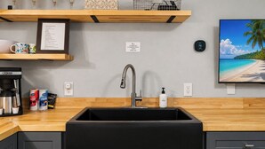 A modern kitchen with a black sink, wooden countertop, and a coffee machine. - Brick House By the Bay | Bay Walk + Local Life (Shalimar)
