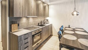 A modern kitchen with wooden cabinets, a built-in oven, a sink, and a dining area with a table and chairs. - Äkäspokka by Interhome (Äkäslompolo)