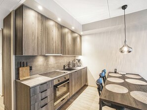 A modern kitchen with wooden cabinets, a built-in oven, a sink, and a dining area with a table and chairs. - Äkäspokka by Interhome (Äkäslompolo)