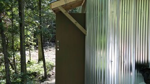 Un bâtiment en métal surmonté d’un toit en bois, entouré d’arbres.