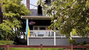 A residential property with a raised garden bed, a white fence, and a house with a dark roof. - Cool apartment in vibrant Seattle neighborhood.Restaurants, bars and Light Rail. (Seattle)