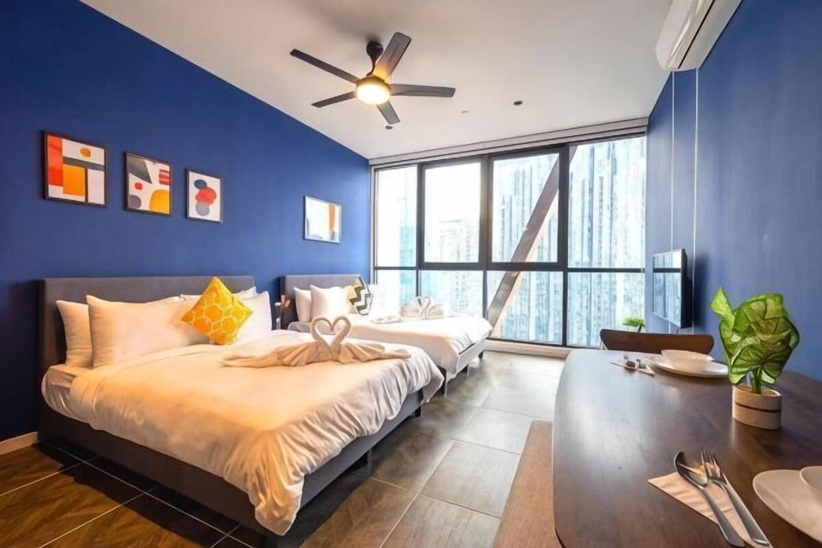Ein Hotelzimmer mit einem großen Bett, einem Schreibtisch und Blick auf die Stadt.
